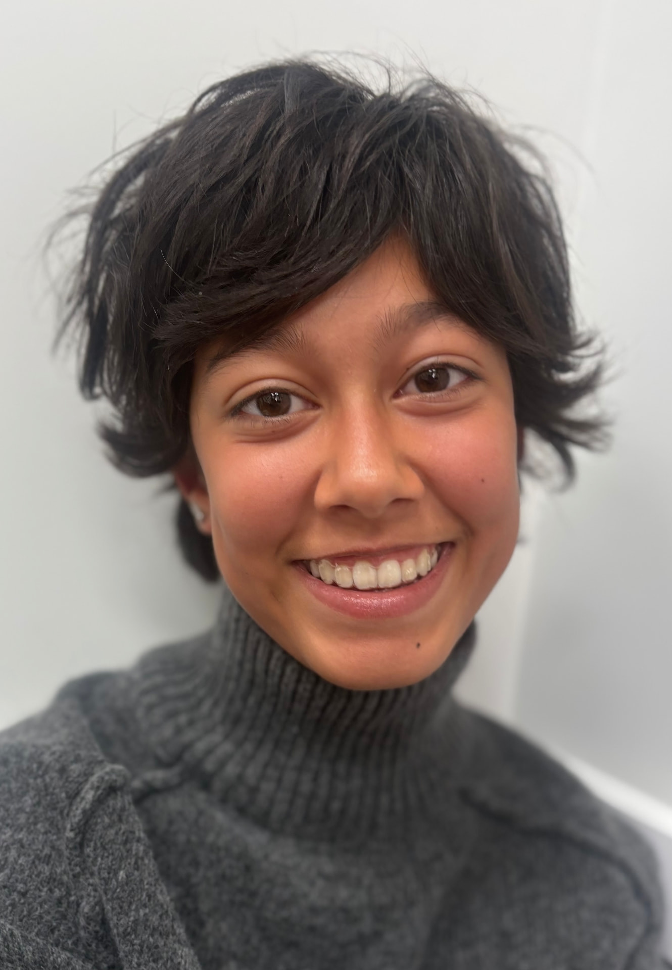 Orthodontic patient smiling in a gray sweater