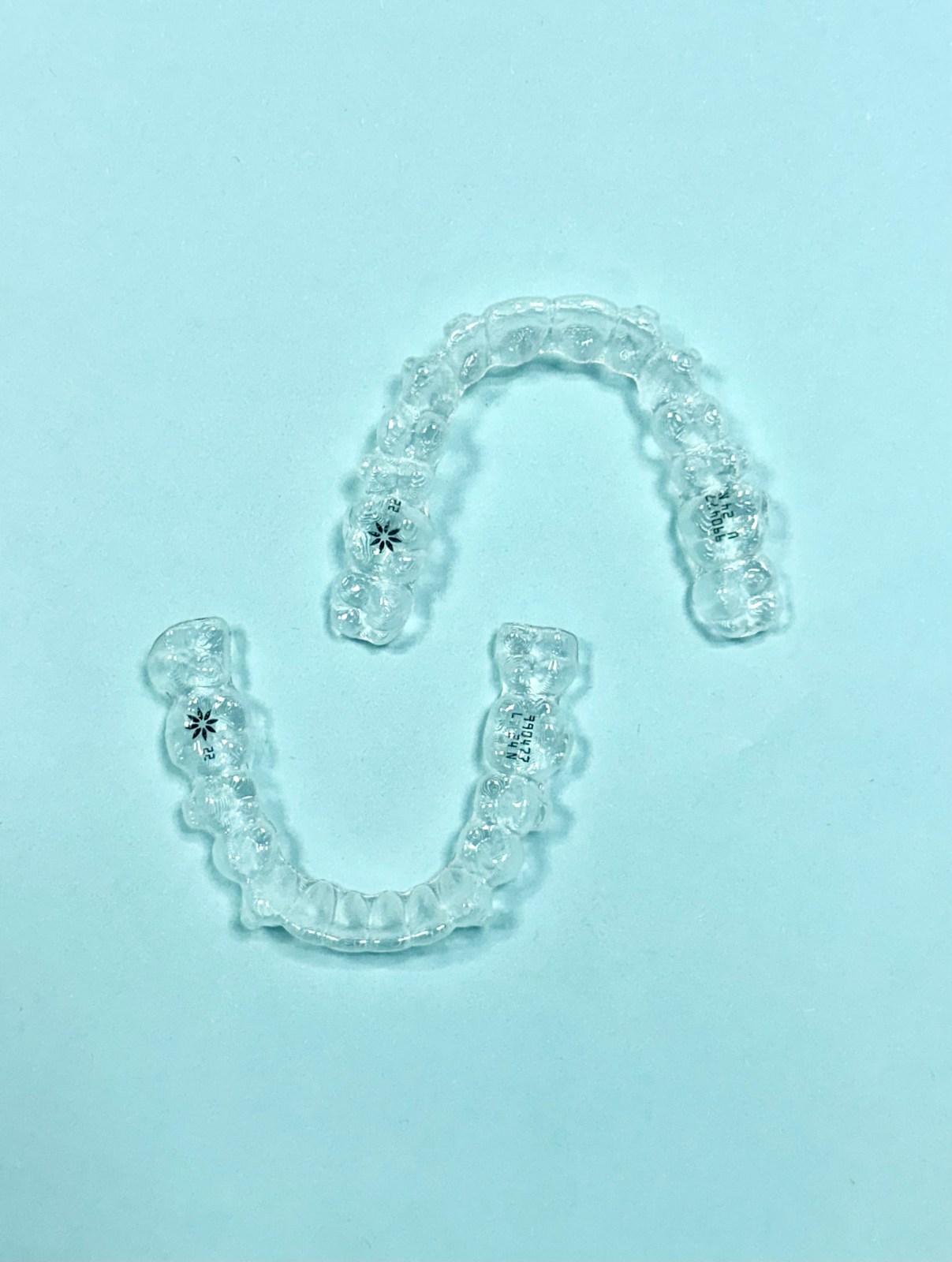 Clear orthodontic retainers on a teal background