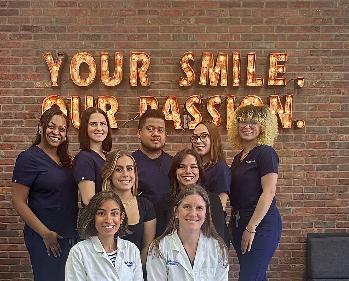 NA Orthodontics office team together beneath the Your Smile Our Passion sign